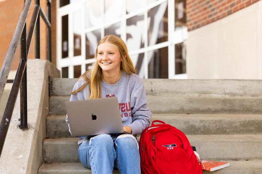 Student with laptop sitting outside