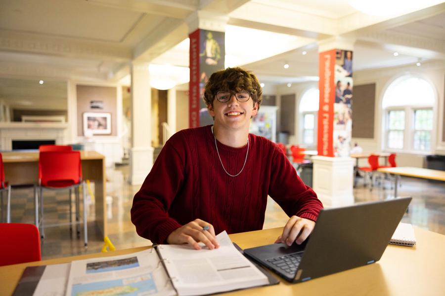 student in the Harned Building with their laptop and notes